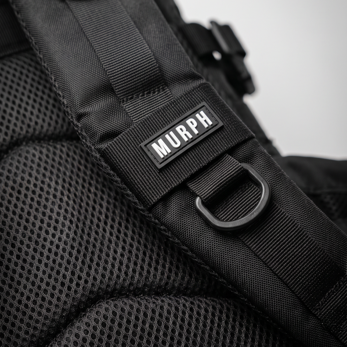 Gros plan de la bretelle et du logo brodé du sac Murph Hero 25L noir
