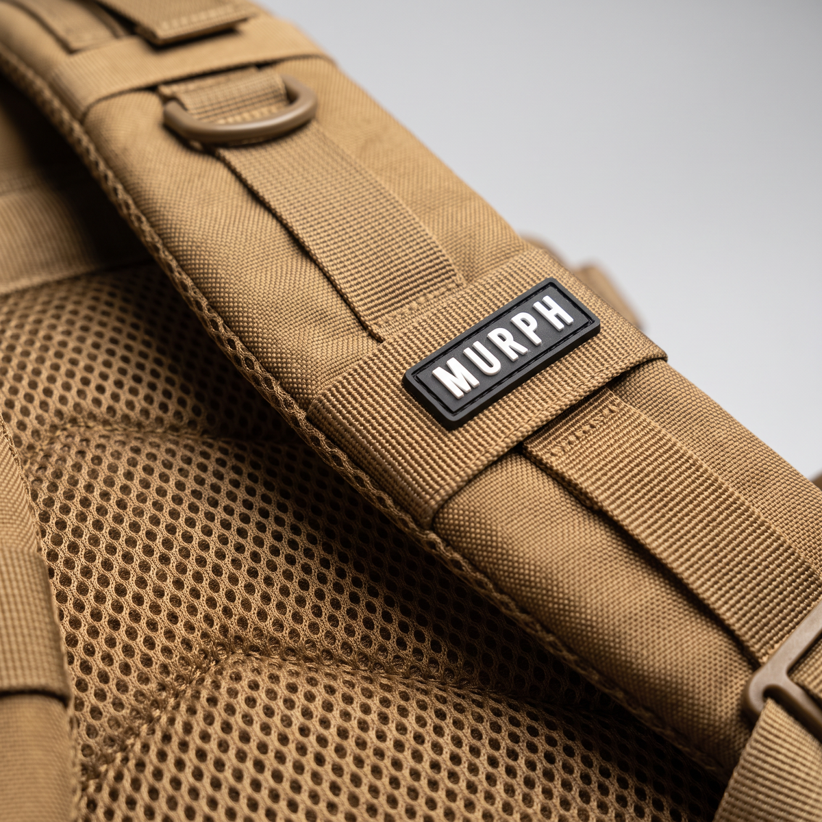 Gros plan de la bretelle et du logo brodé du sac Murph Hero 25L marron